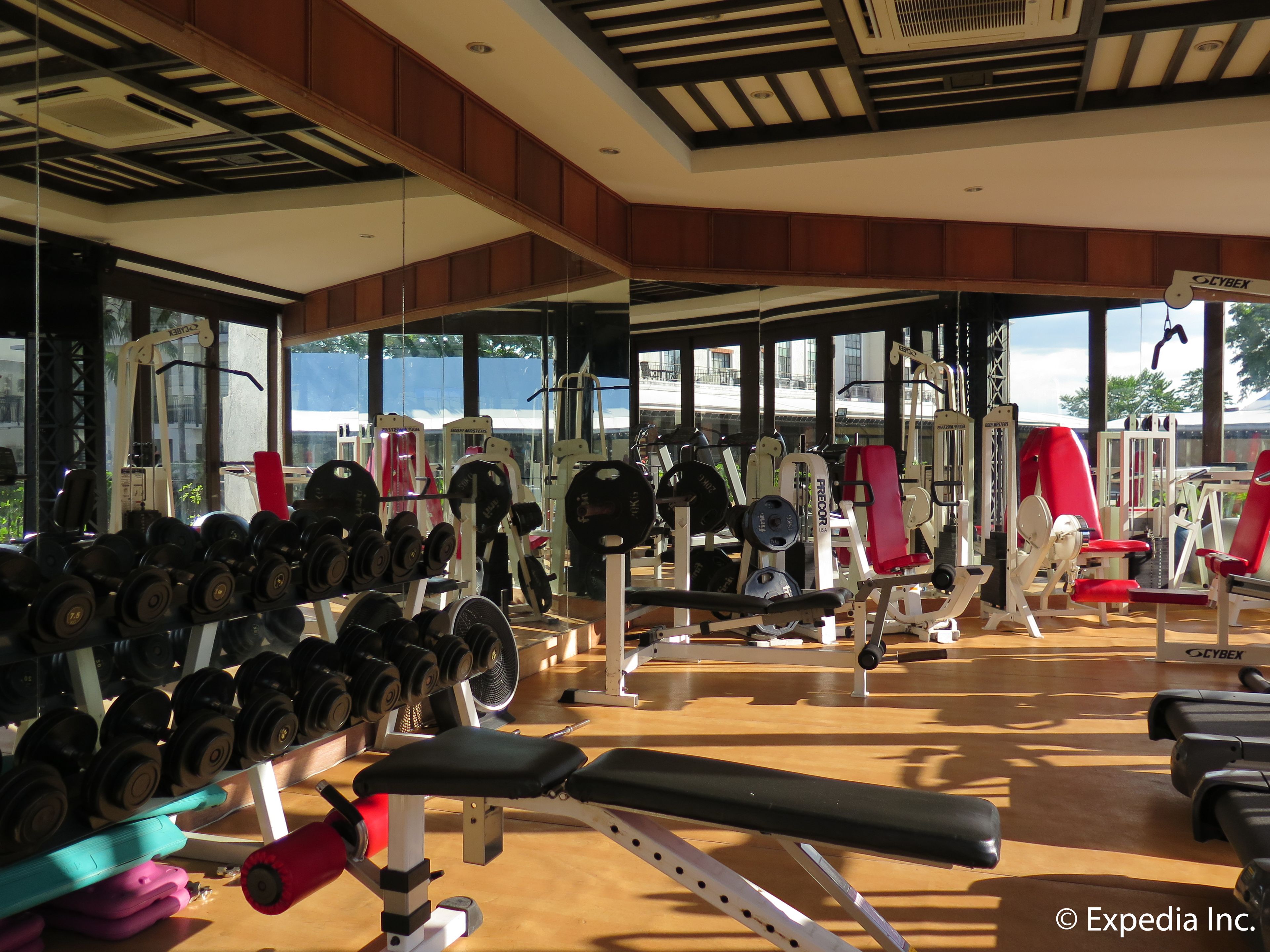A gym with various exercise equipment, large windows, and a view of the outdoors.