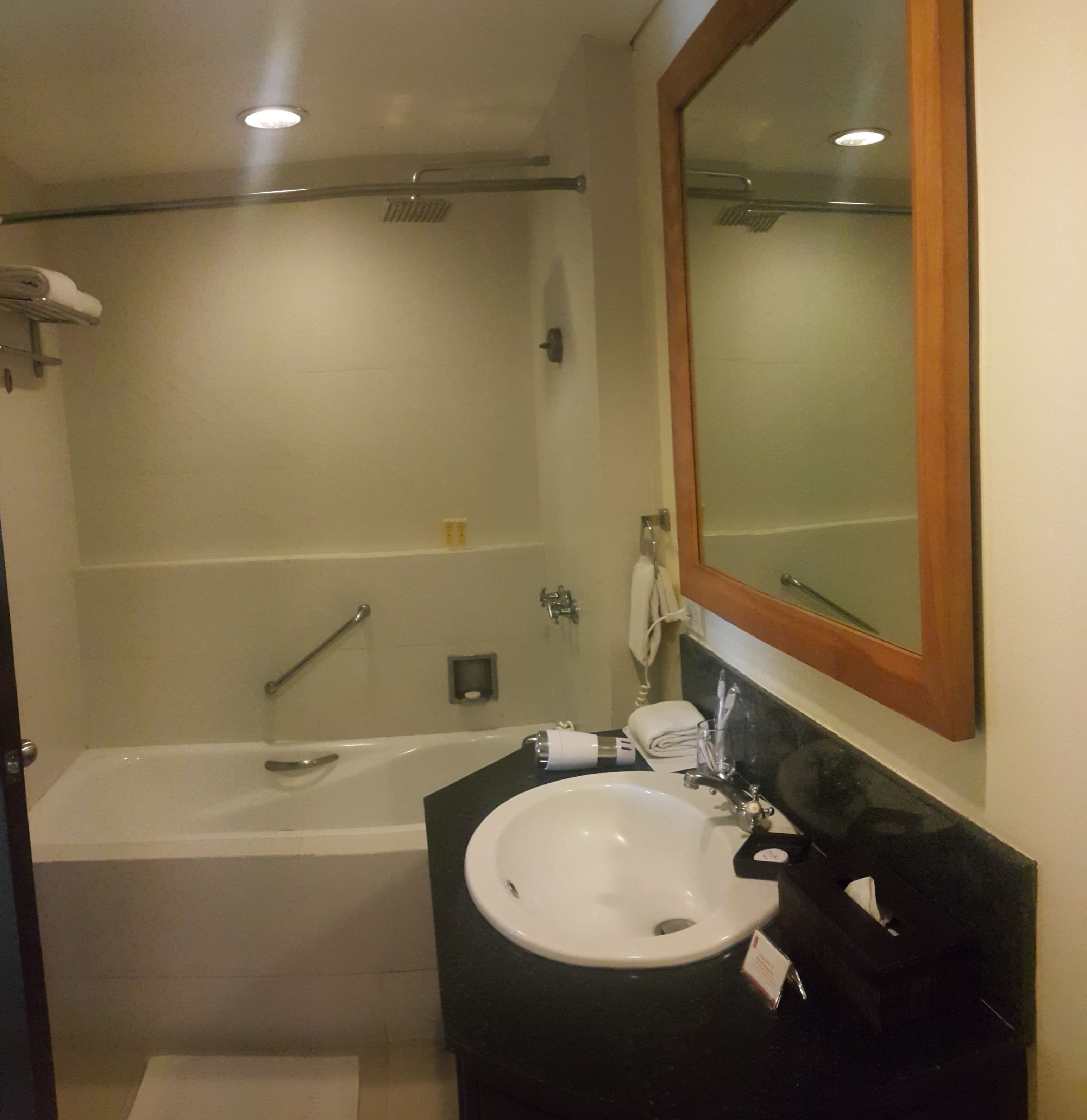 A bathroom with a bathtub, a sink, a mirror, and a towel rack.