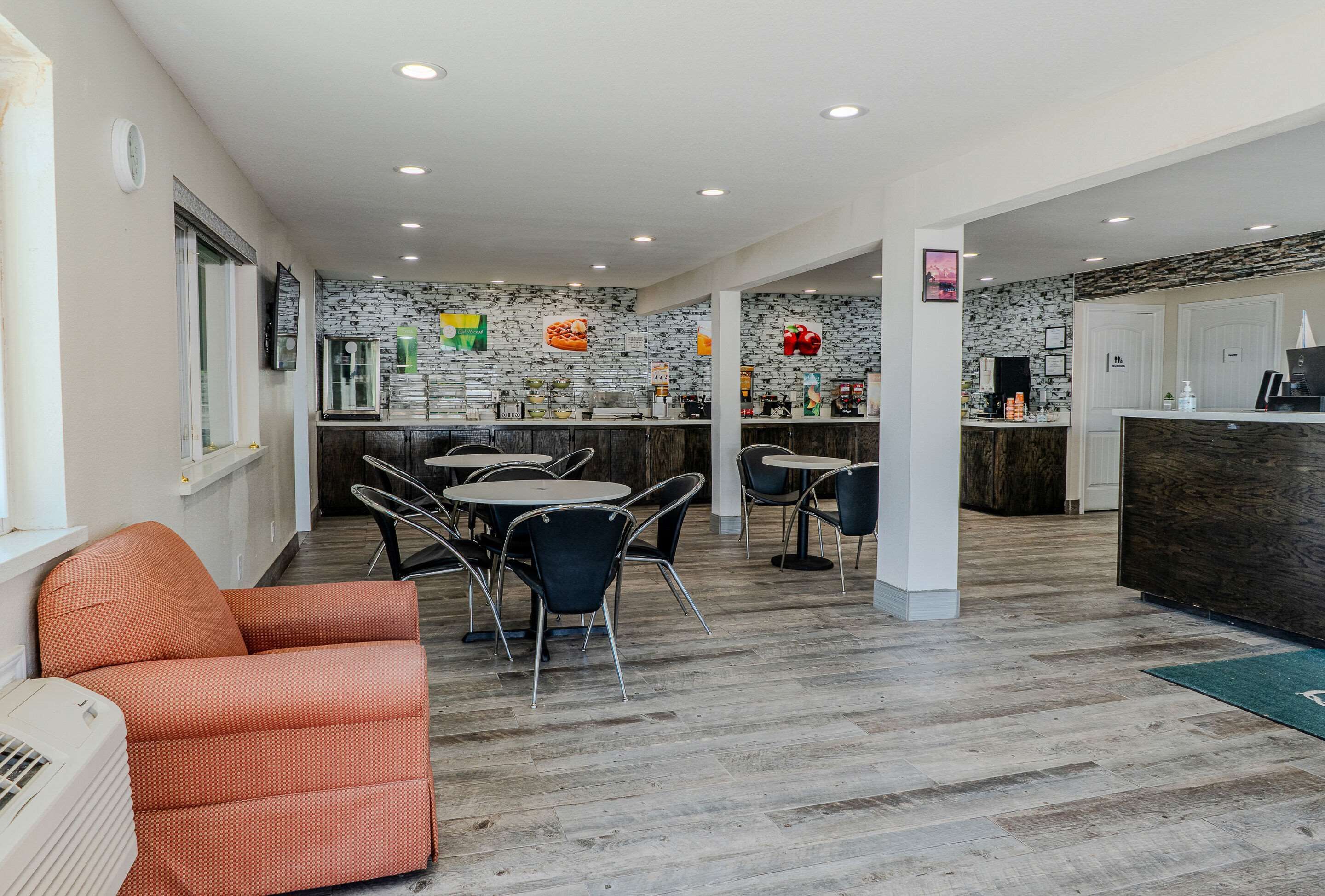 Un hall d’hôtel moderne avec un espace repas, un comptoir d’accueil et une cuisine en arrière-plan.
