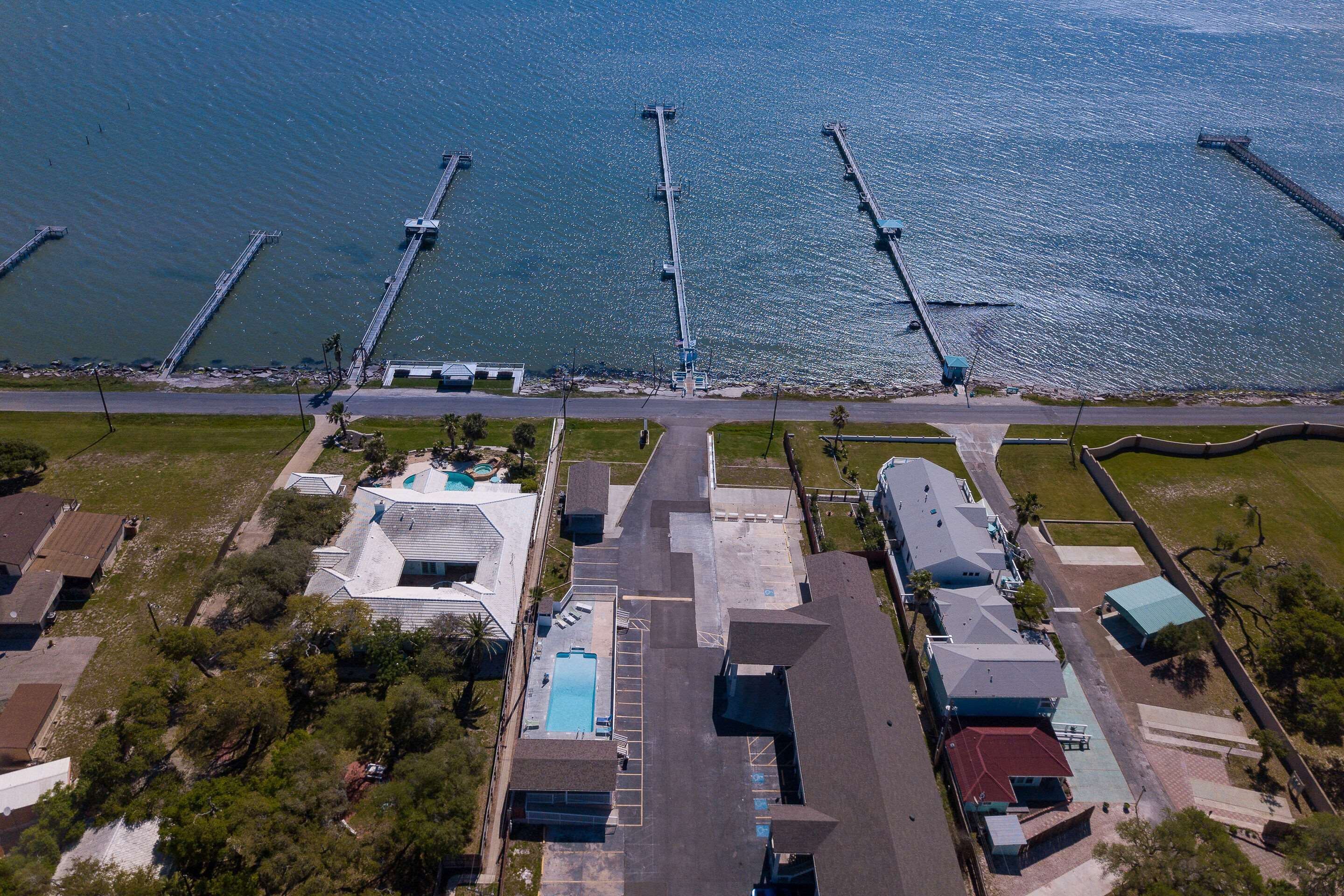 Vista aérea de una propiedad costera con piscina, varias edificaciones y muelles que se adentran en el agua.