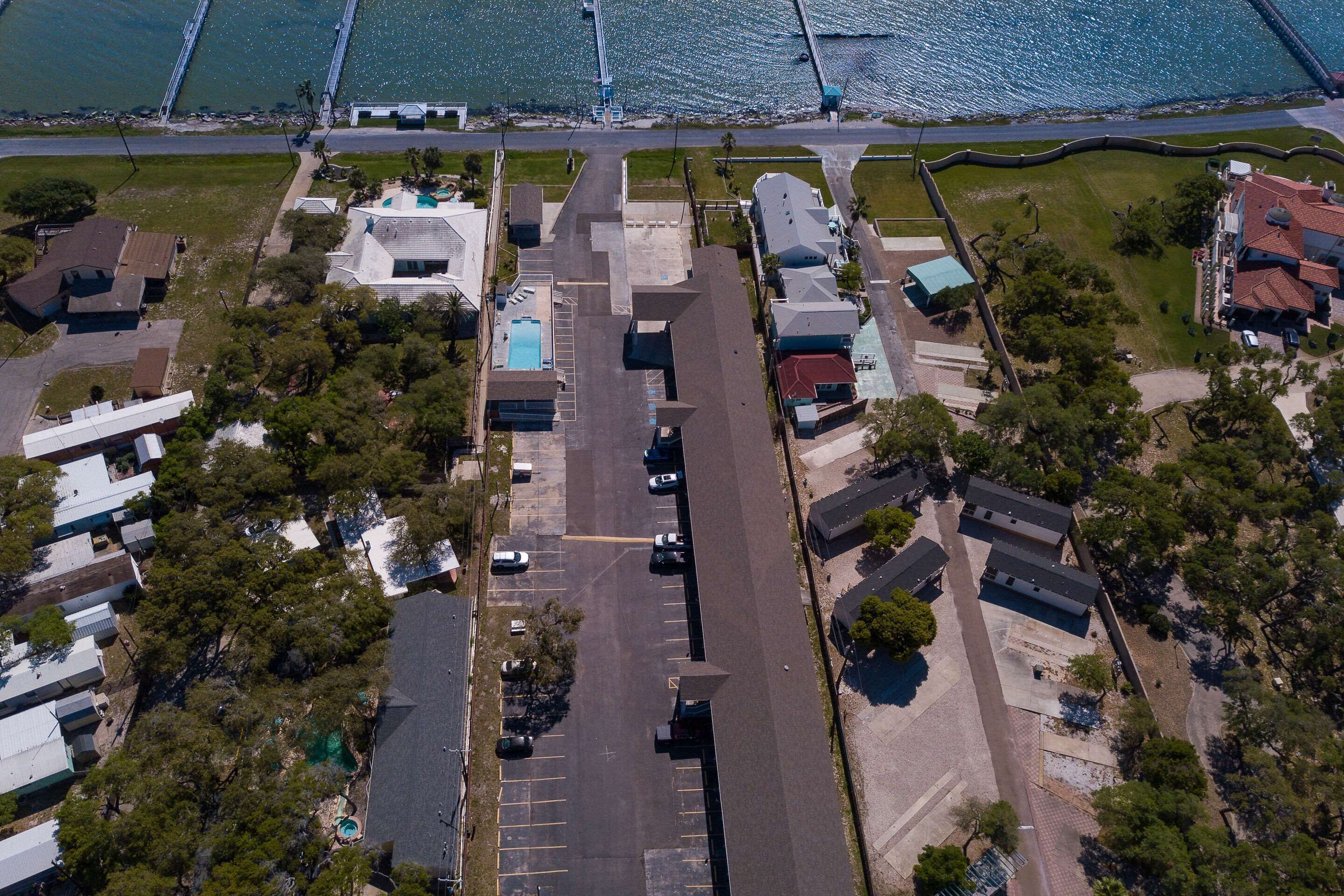 An aerial view of a residential area with houses, a swimming pool, and a road.