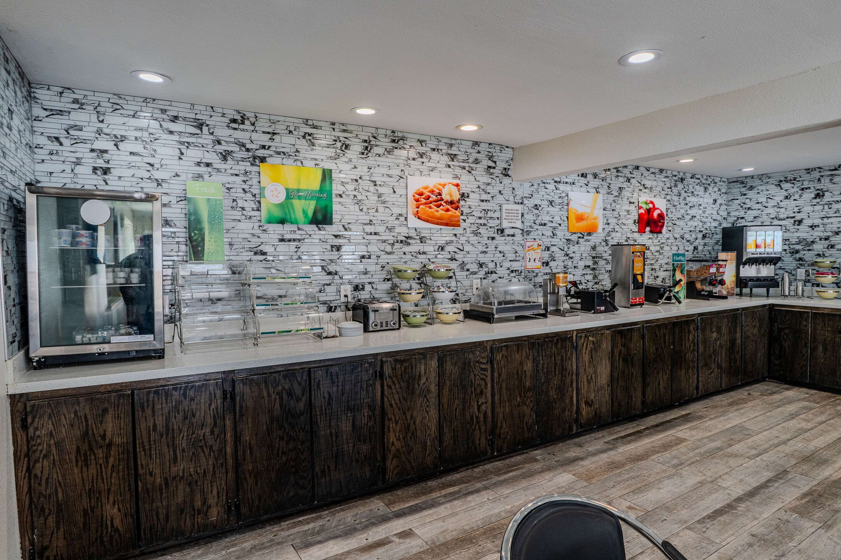 Un bar pour prendre le petit-déjeuner, avec un mur recouvert de briques apparentes, un réfrigérateur et divers aliments pour le petit-déjeuner.