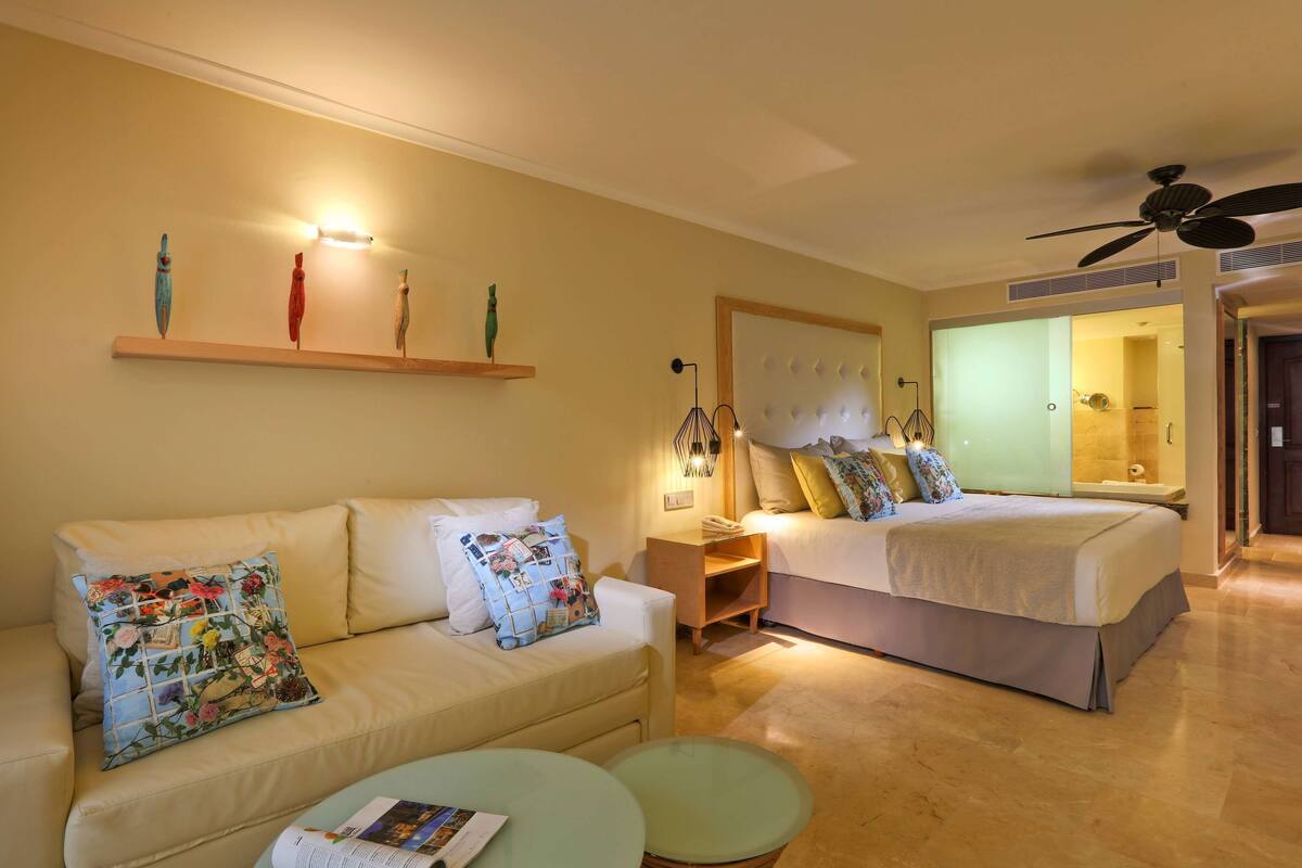 Een hotelkamer met een bank, een bed, een kleine tafel en een nachtkastje.