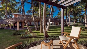 A wooden deck with a thatched-roof structure, palm trees, and a lounge chair. - Grand Palladium Palace Resort Spa & Casino - All Inclusive (Punta Cana)
