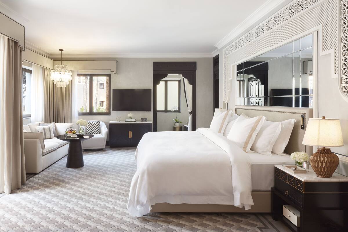 Ett hotellrum med en stor säng, en soffa, en TV och en dekorativ spegel.