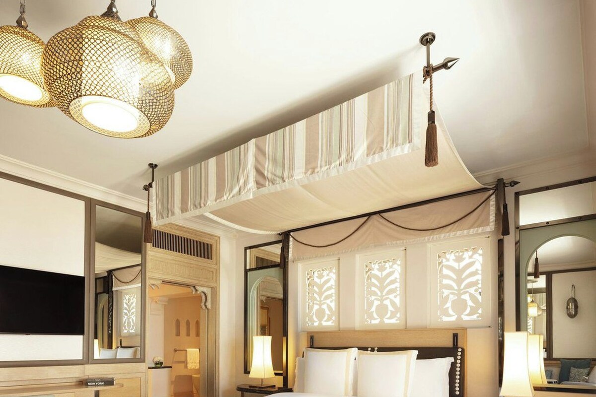 A hotel room with a large bed, bedside tables, a desk, and a television.