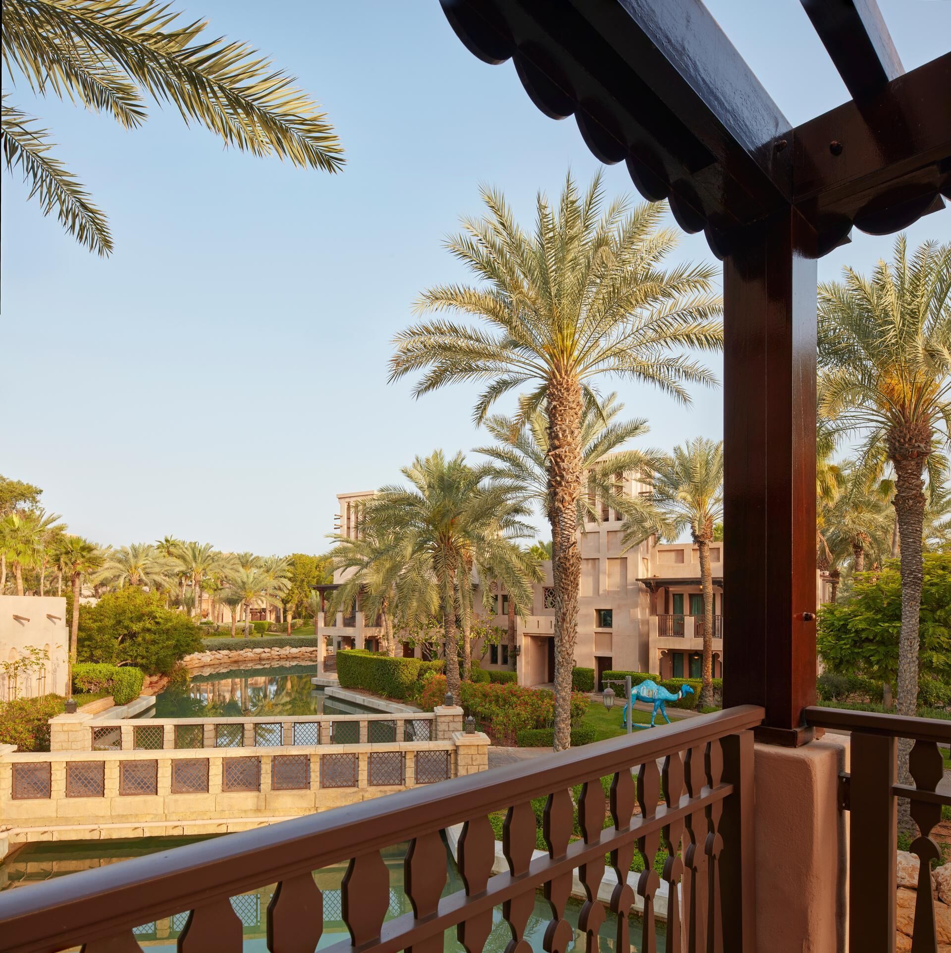 Vista de un resort con palmeras, piscina y edificios con balcones.