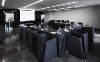 Een vergaderzaal met een lange tafel, stoelen en een scherm voor een beamer.