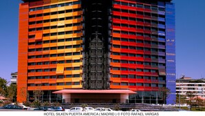 A multi-story hotel with a distinctive facade featuring a central black structure and colorful panels. - Hotel Puerta América (Madrid)