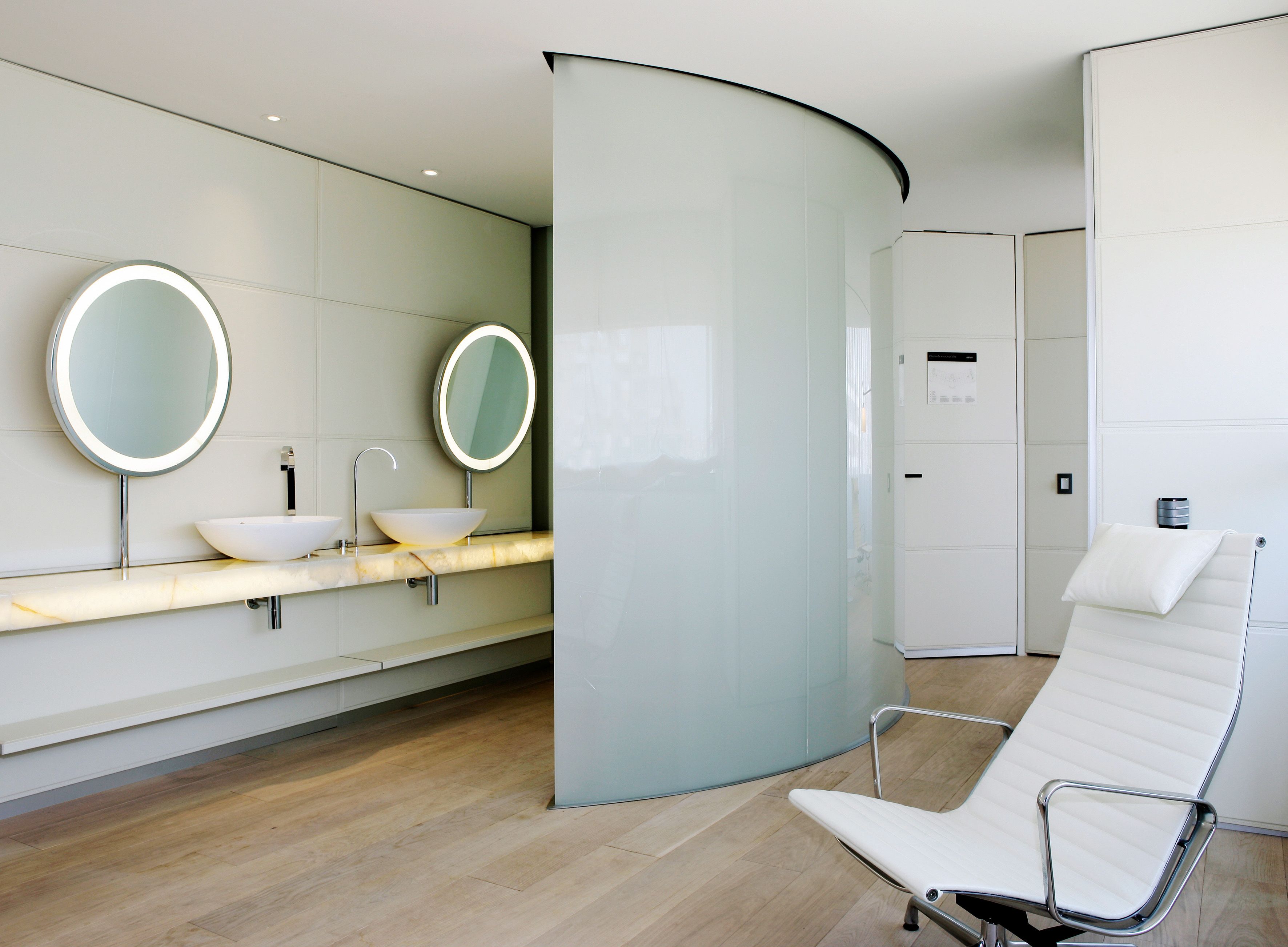 Un baño moderno con dos lavamanos, un espejo y una silla blanca.