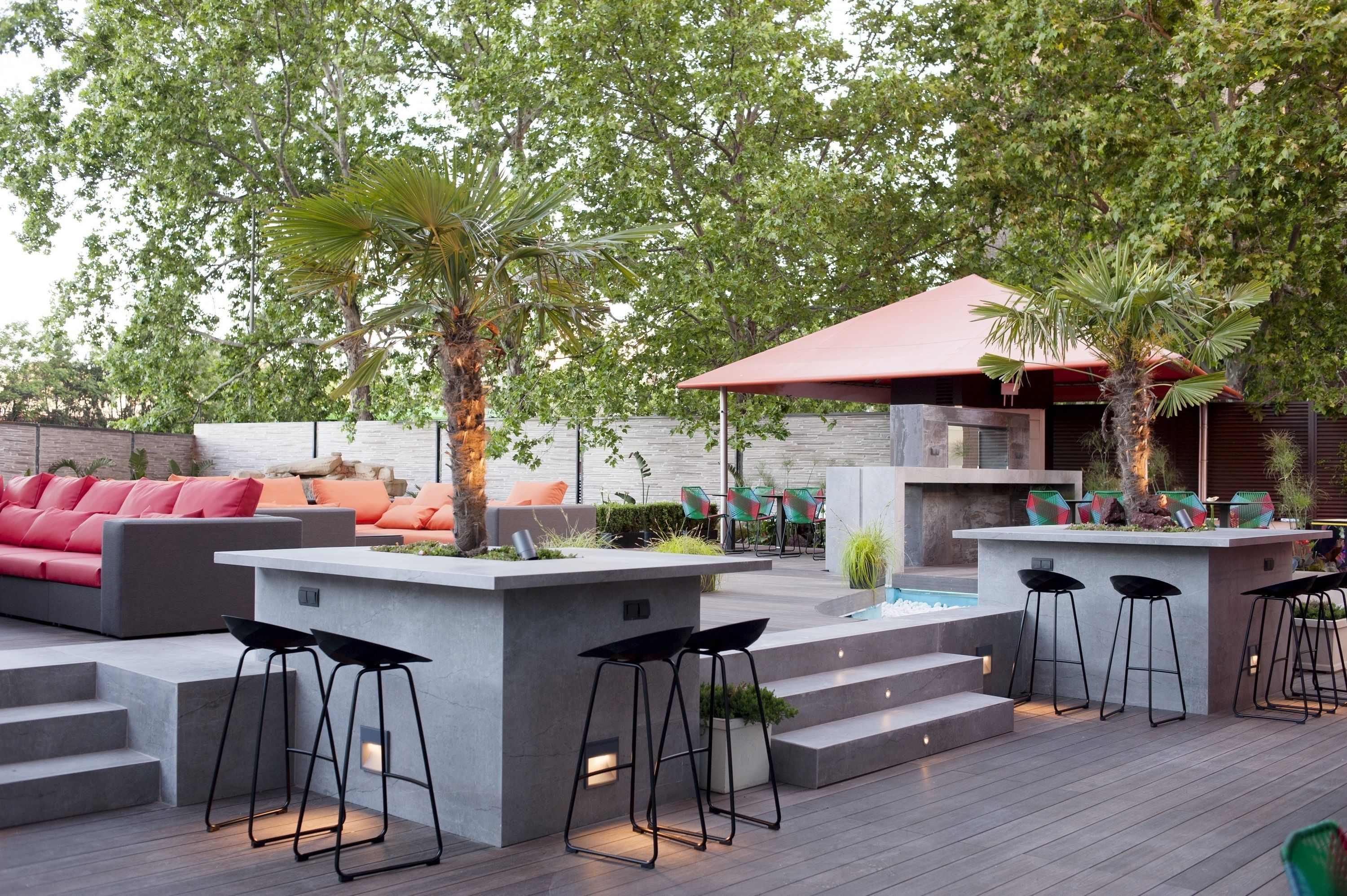 Une terrasse extérieure dotée d’un bar moderne, de coins salon et d’une piscine.