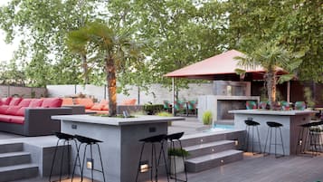 An outdoor patio with a modern bar area, seating, and a pool.