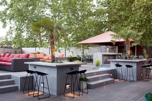 Patio esterno con zona bar moderna, posti a sedere e piscina.