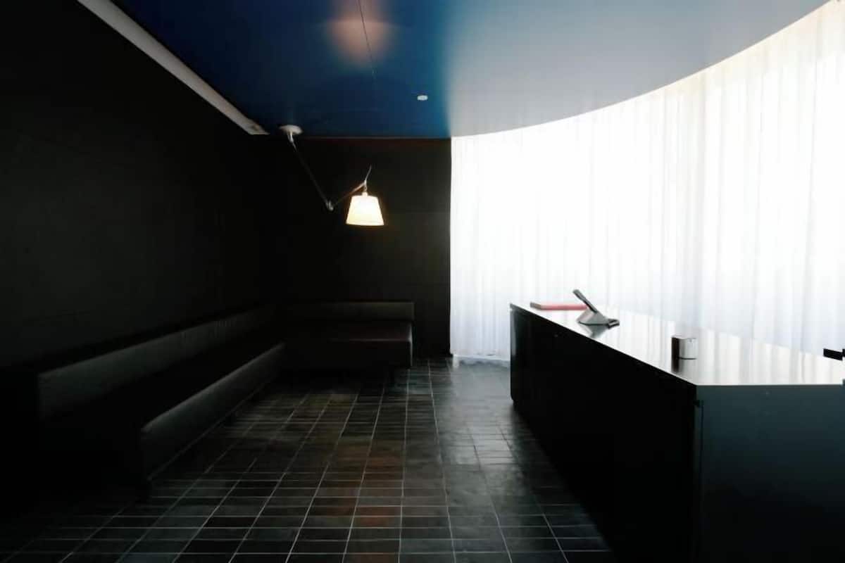 A modern interior with a reception desk, a bench, and a hanging light fixture.