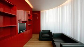 Una sala de estar moderna con paredes rojas, un televisor de pantalla plana y sofás de cuero negro.
