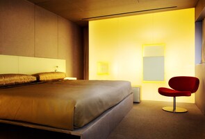 Ein modernes Schlafzimmer mit einem großen Bett, einem roten Sessel und einem Nachttisch.