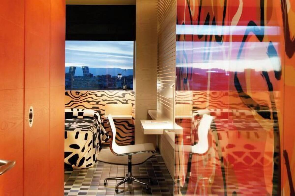 A modern bathroom with a patterned shower curtain, a white sink, and a chair.