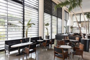 Un ristorante moderno con ampie vetrate, arredi bianco e nero e piante da interno.