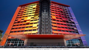 A multi-story hotel with a modern design, featuring a prominent central entrance and balconies on each floor. - Hotel Puerta América (Madrid)