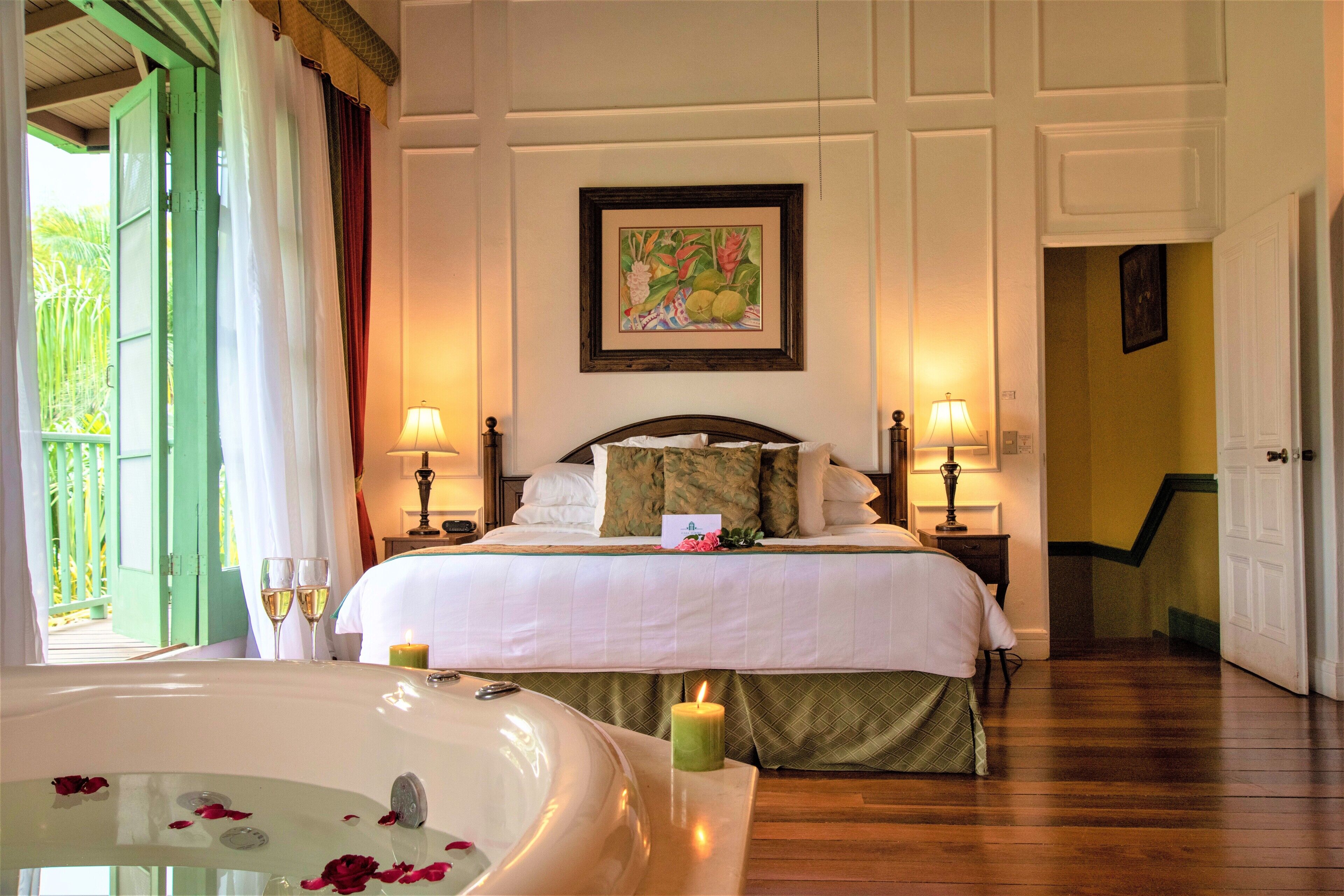 A hotel room with a bed, two bedside lamps, a framed picture on the wall, and a view of the outside.