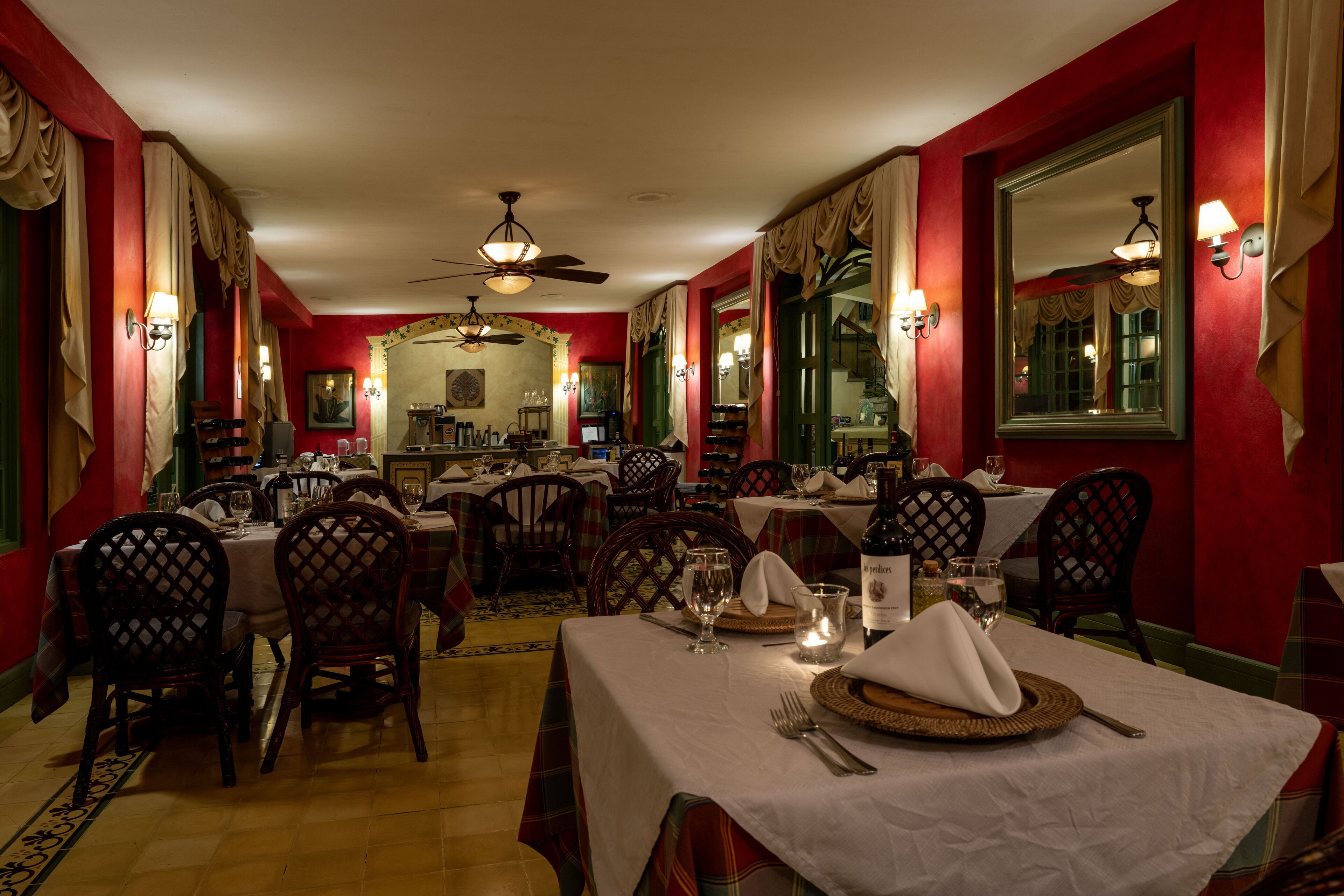 A restaurant with red walls, multiple tables, and chairs.