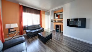 Ein modernes Wohnzimmer mit Sofa, Hocker und einem an der Wand befestigten Fernseher.