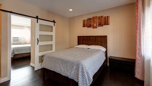 Ein Schlafzimmer mit Bett, einer Bank, einer Schiebetür und einer Wand mit Kunstwerken.