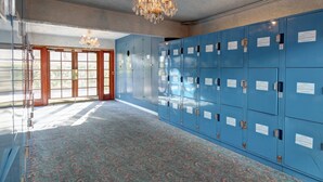 Ein Zimmer mit blauen Schließfächern, einer Kristallleuchtre und einem gemusterten Teppich.