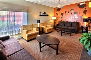 A hotel room with a sofa, armchairs, a coffee table, and a large window with sheer curtains. - Sleep Inn and Suites - Ocala / Belleview (Ocala)