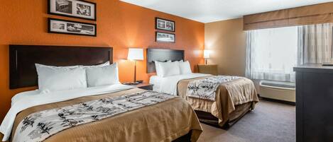 Una habitación de hotel con dos camas, un ventanal con cortinas y lámparas fijadas a la pared.