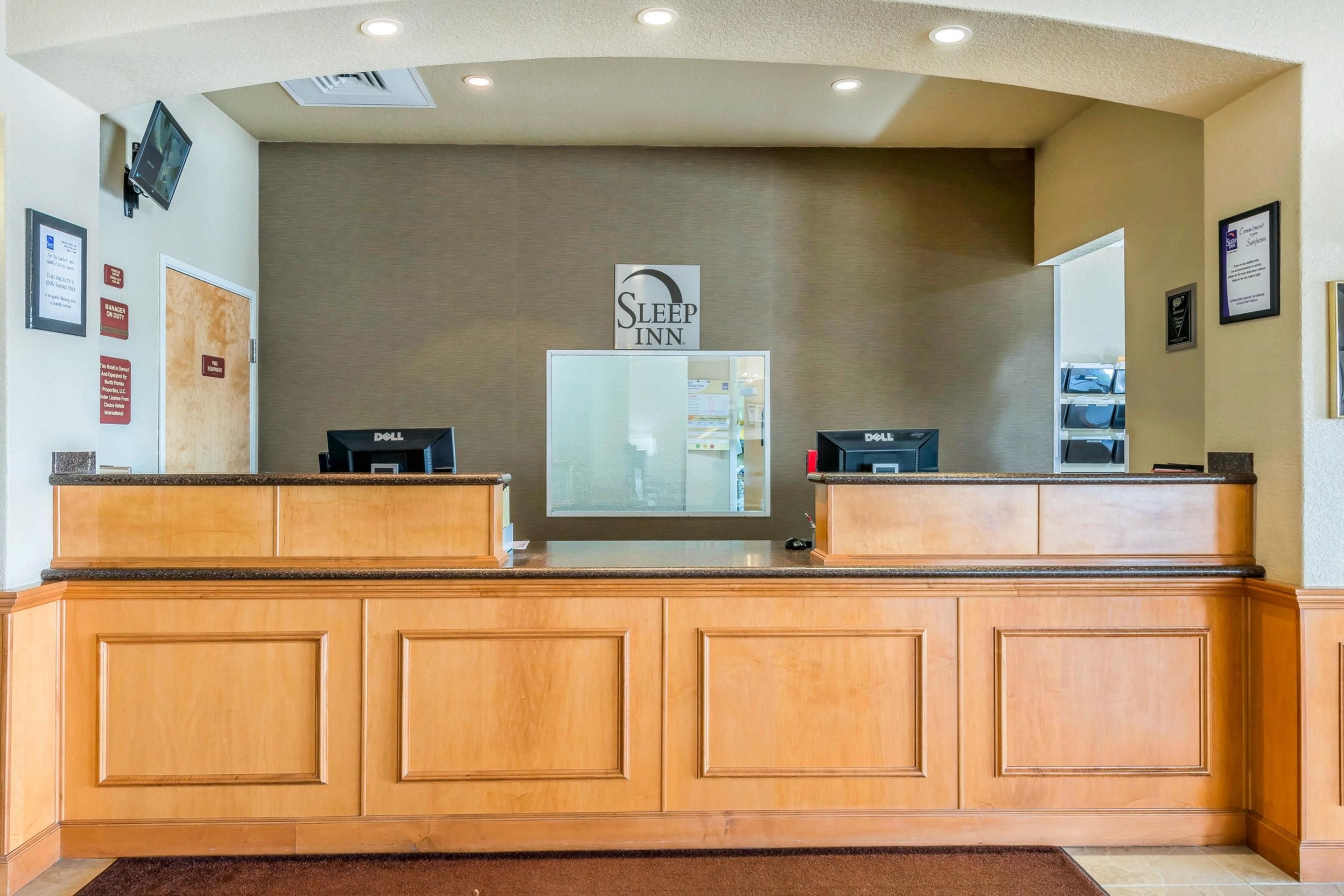 A reception desk with a sign reading "Sleep Inn" above it, two computers, and a mirror on the wall.