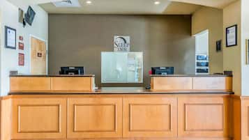 A reception desk with a sign reading "Sleep Inn" above it, two computers, and a mirror on the wall.