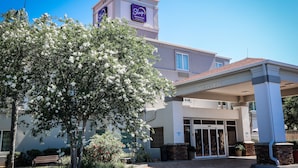 A Sleep Inn & Suites building with a clear entrance, a covered waiting area, and a sign indicating a clearance of 14'0". - Sleep Inn and Suites - Ocala / Belleview (Ocala)