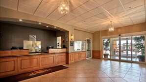 A reception area with a wooden counter, a sign reading "Sleep Inn," and a large glass door leading outside. - Sleep Inn and Suites - Ocala / Belleview (Ocala)