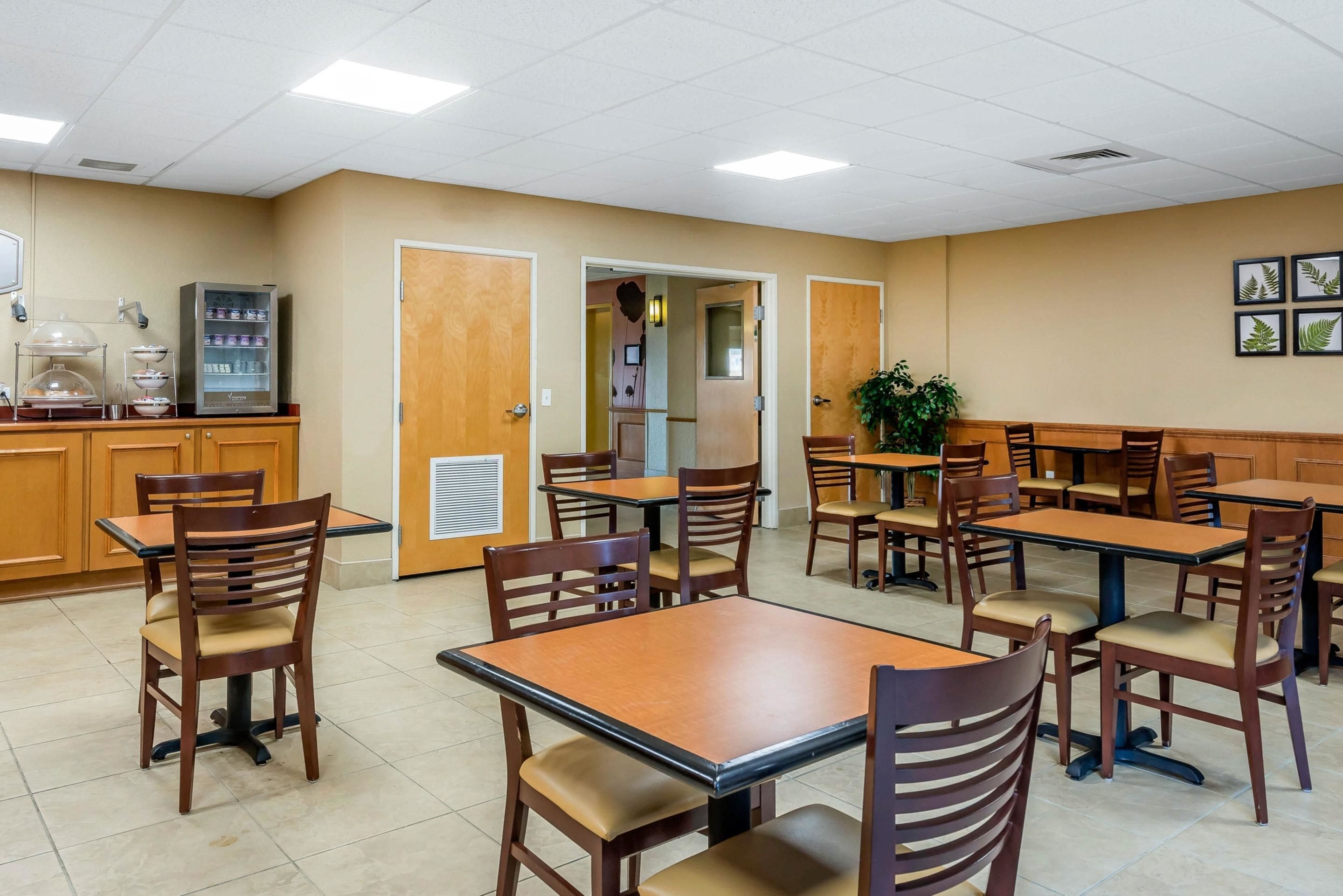 A dining area with multiple tables and chairs, a vending machine, and a door leading to another room.