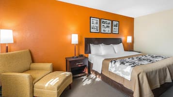 A hotel room with a bed, two bedside tables with lamps, a chair, and a wall with three framed pictures.