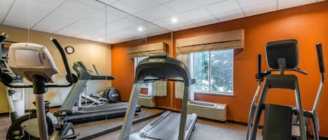 Un gimnasio con cintas de correr, elípticas y una bicicleta estática.