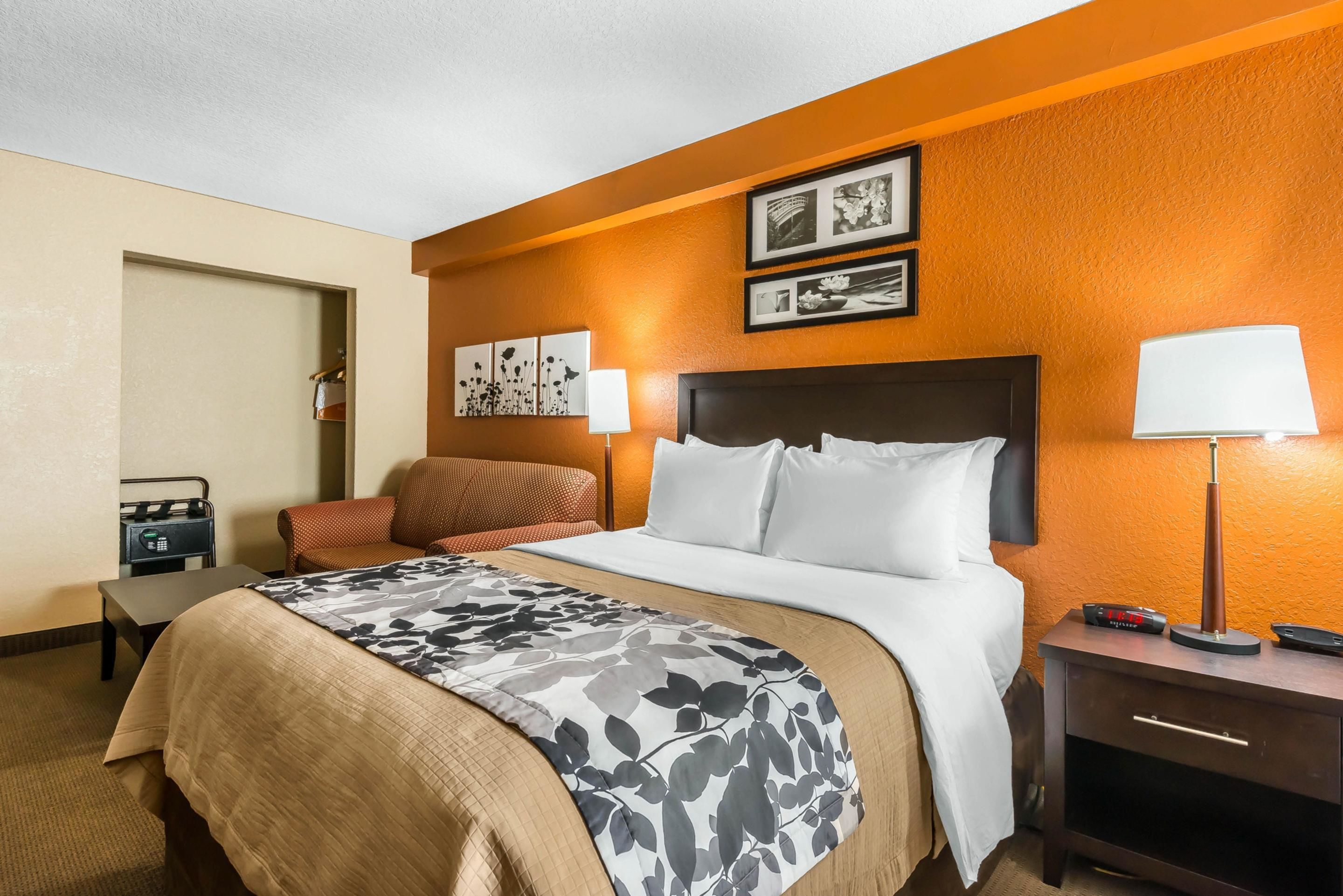 A hotel room with a bed, bedside table, lamp, and a chair.