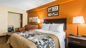 A hotel room with a bed, bedside table, lamp, and a chair.