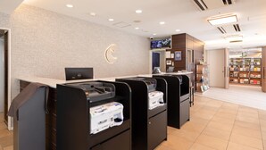 Un espace d’accueil au design moderne, comprenant un comptoir de réception, un écran numérique et une horloge murale.