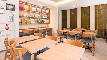 Una biblioteca moderna con mesas y sillas de madera, estanterías y plantas decorativas.