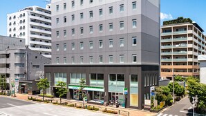 Un hôtel moderne doté d’une entrée centrale, de plusieurs étages et offrant une vue sur un ciel dégagé.