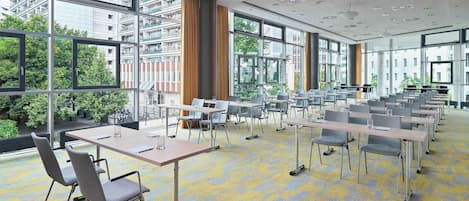 A modern conference room with large windows, multiple tables, and chairs.