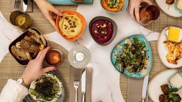 A table set with various dishes, including hummus, salad, and grilled shrimp, indicating a meal setting.