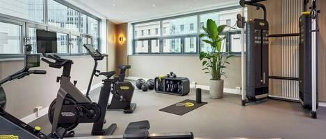 A modern gym with cardio machines, free weights, and a pull-up bar area.