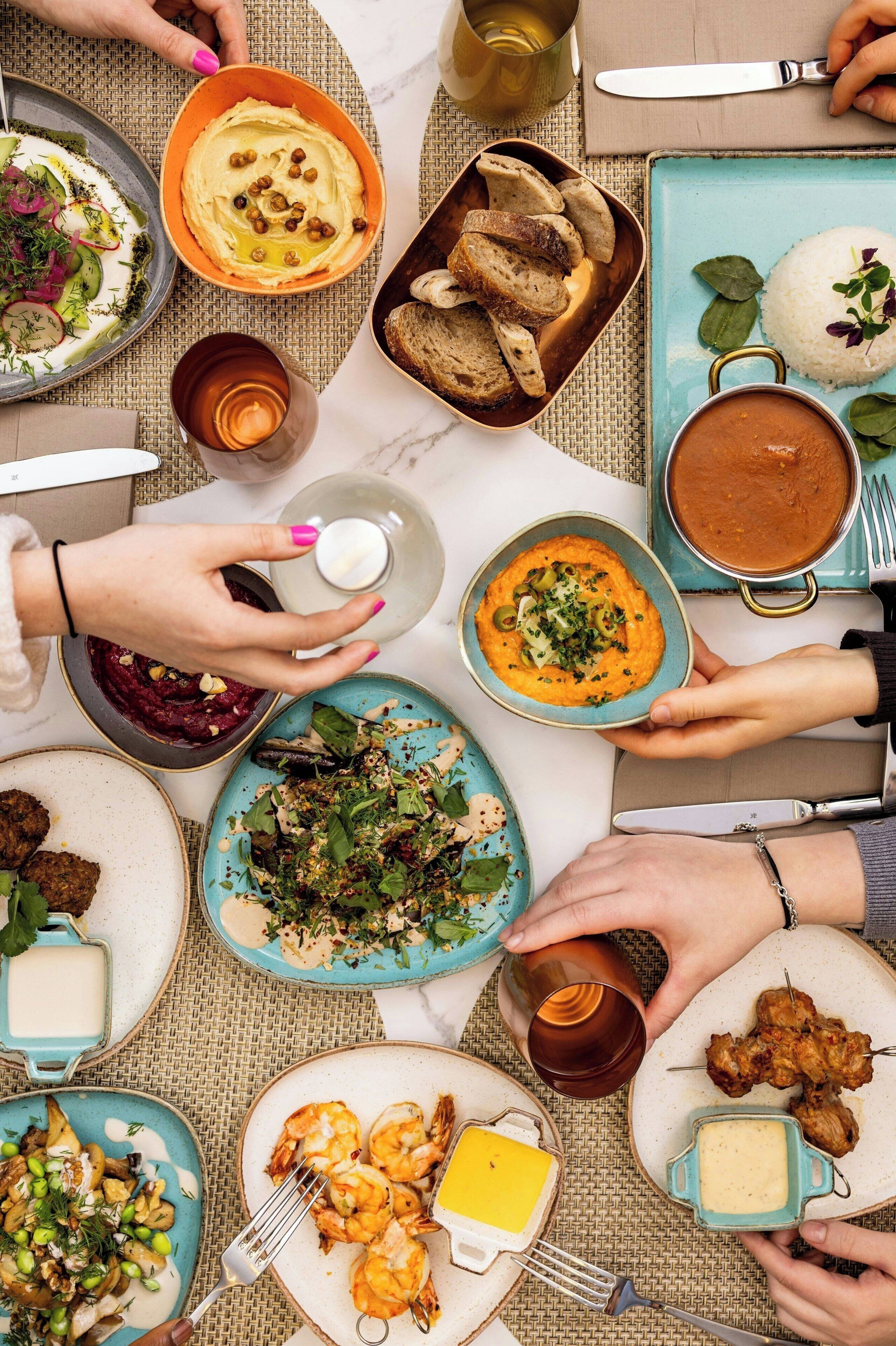 A table with various dishes, including hummus, rice, and shrimp, suggesting a meal setting.