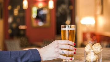 Una mano che tiene un bicchiere di birra accanto a un altro bicchiere di birra e un piccolo bicchierino di biscotti.