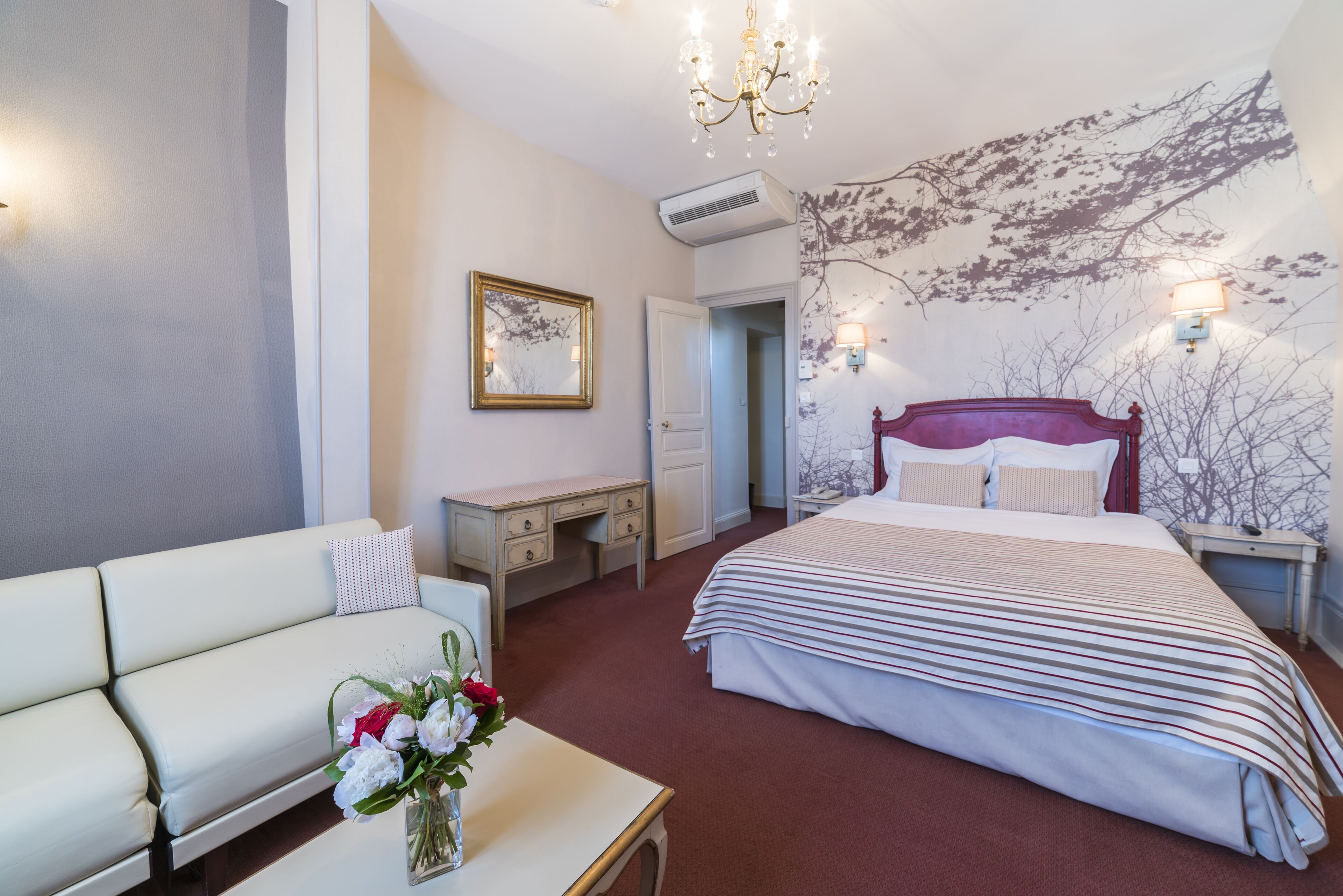 Une chambre d’hôtel avec un grand lit, un canapé, un bureau et un miroir fixé au mur.