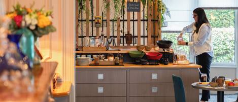 A kitchen area with a person preparing food, a wooden counter, and various kitchen utensils.