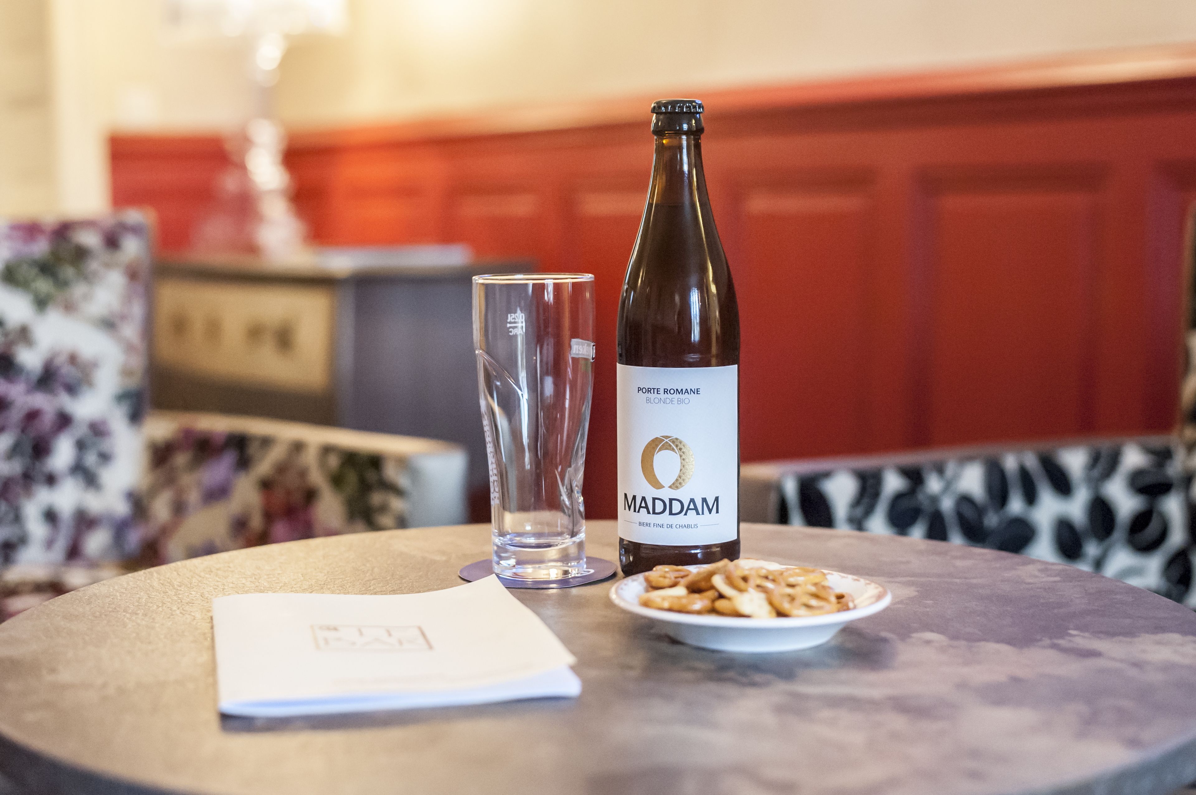 Una botella de vino, una copa y un plato de aperitivos sobre una mesa redonda.